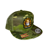 A green camouflage trucker hat with a mesh back, featuring a circular embroidered patch on the front that reads 'BUILDING SHIT YOU CAN'T' with a skull wearing a hard hat.