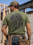 Olive green t-shirt with a motivational quote, saying "There is more of us than them" on the back standing in a construction site.