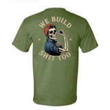 An army green short-sleeve t-shirt shown from the back, featuring a graphic of a skeleton woman with a red polka-dot bandana and blue shirt flexing, with the text 'WE BUILD SHIT TOO' in a distressed beige font.