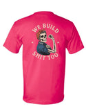 A bright pink short-sleeve t-shirt shown from the back, featuring a large graphic print of a skeleton flexing and the text 'WE BUILD SHIT TOO' in cream.